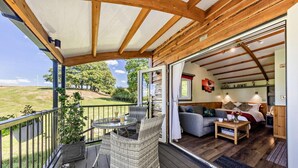 Une pièce confortable avec un lit, un canapé et une table à manger. Il y a un balcon avec une table et des chaises.