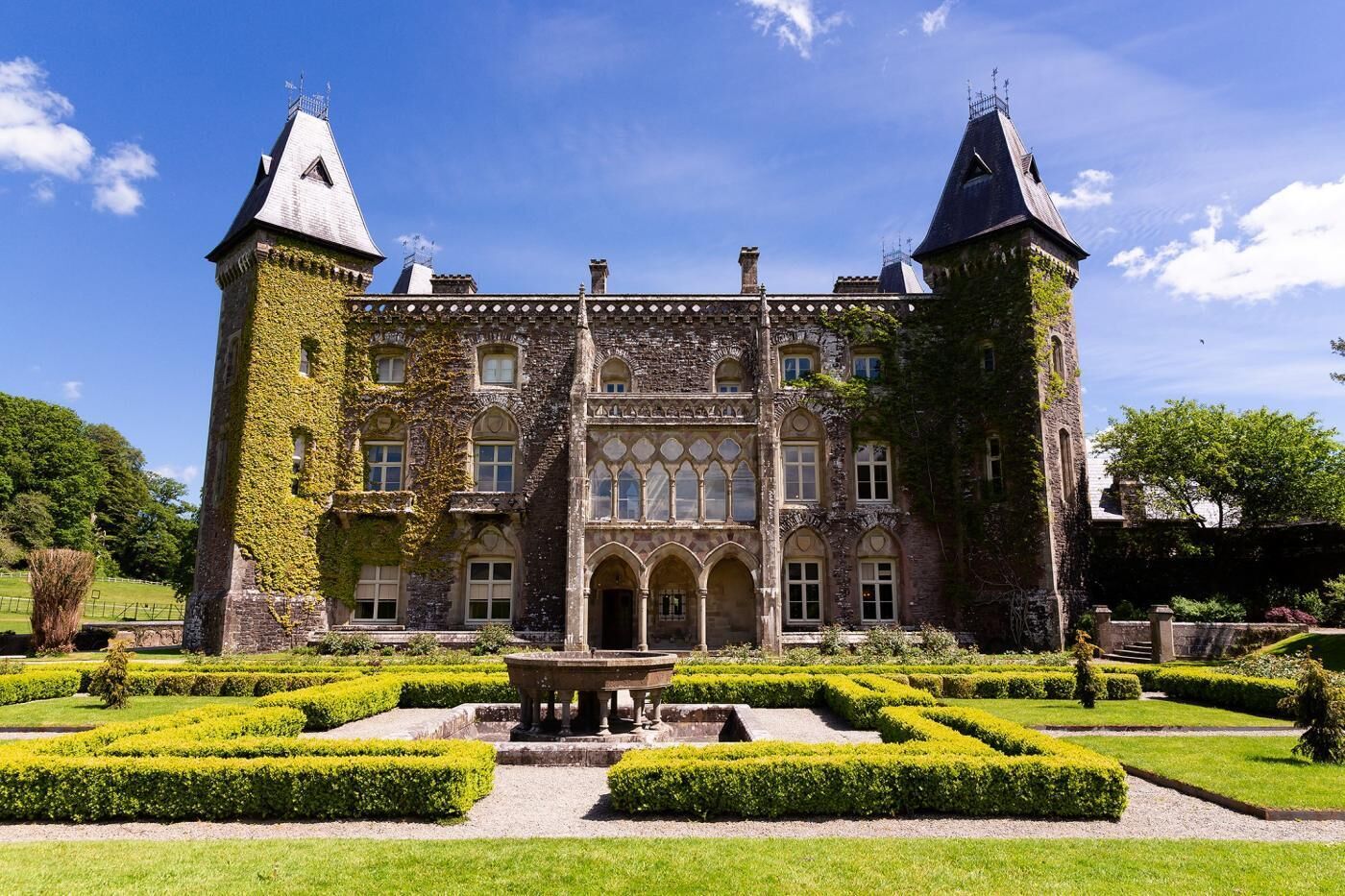 A historic castle with a symmetrical facade, arched windows, and two prominent towers.