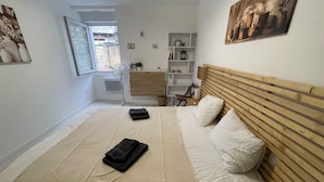 A bedroom with a bed, bedside tables, a wooden headboard, a window, and a door. - Villa Margot (Fumel)