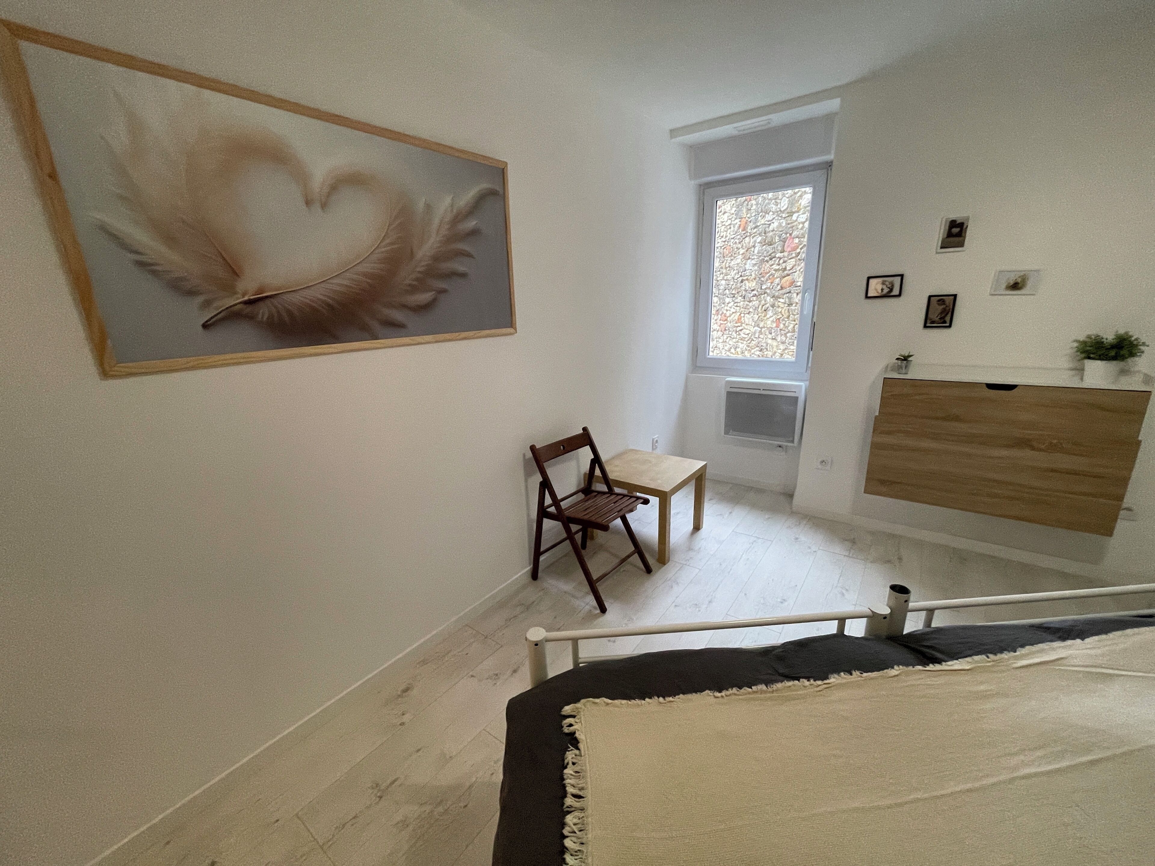 Een kamer met een bed, een stoel, een tafel, een schilderij, een raam en een dressoir.