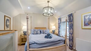 Una cama con dosel de madera, un candelabro y cortinas estampadas.