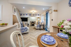 A modern living room with a fireplace, a dining area with blue and white patterned plates, and a herringbone wood floor. - 1 Bed in Conwy (oc-r33031) (Conwy)