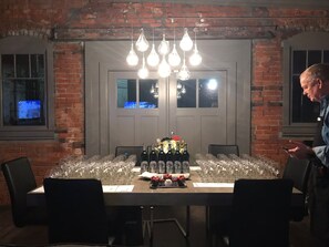 A dining table set with wine bottles, glasses, and a cake centerpiece in a room with brick walls and a large window. - Luxury Studio in KC Crossroads with parking, covered patio (Kansas City)