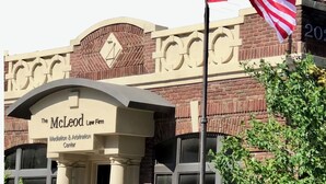 Un edificio con un cartello che riporta la scritta "The McLeod Law Firm Mediation & Arbitration Center".