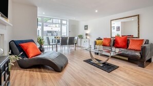 A modern living room with a glass coffee table, leather sofas, and a dining area with chairs. - 3 Bed in Sandsend (oc-a33016) (Sandsend)
