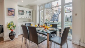 A dining area with a glass table and chairs, a vase of flowers, and a view of a staircase and outdoor area. - 3 Bed in Sandsend (oc-a33016) (Sandsend)