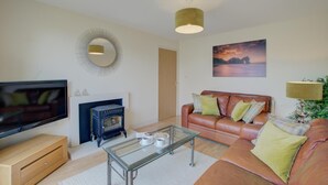 Ein Wohnzimmer mit Fernseher, Kamin, Sofa und Couchtisch.