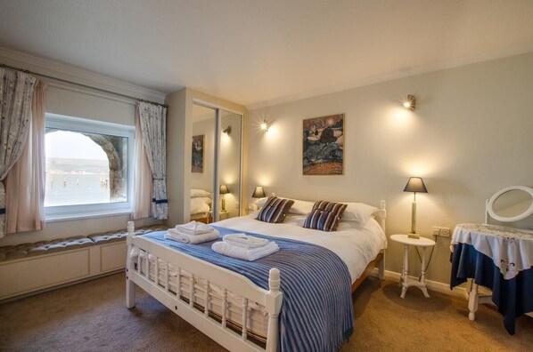 Ein Schlafzimmer mit Bett, Nachttischen, einem Spiegel und einem Fenster mit Vorhängen.
