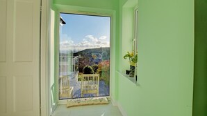 A narrow hallway with a glass door leading to a balcony with a view of a mountainous landscape. - 4 Bed in Morcombelake (oc-wy403) (Morcombelake)