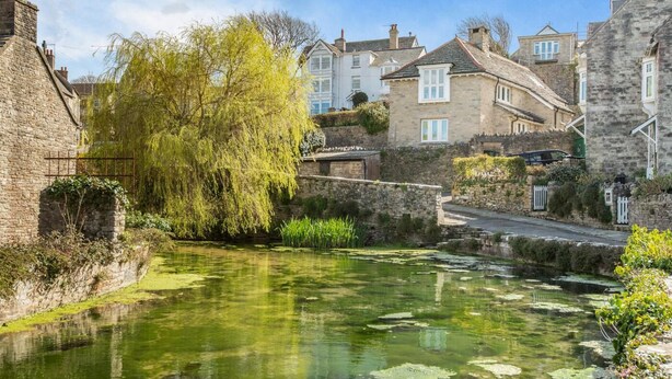 A historic stone building with a narrow waterway and willow trees. - 3 Bed in Swanage (oc-wy557) (Swanage)
