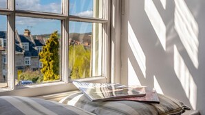 A window with a view of buildings and trees, a pillow, and a magazine on a windowsill. - 3 Bed in Swanage (oc-wy557) (Swanage)
