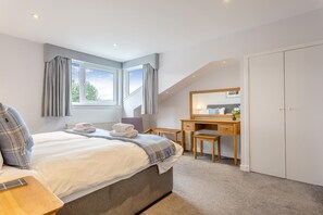 A bedroom with a bed, a desk, a chair, a wardrobe, and a window with curtains. - 3 Bed in Ullapool (oc-s33063) (Ullapool)