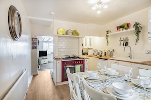 A modern kitchen with a central island, white cabinetry, and a dining area set for six. - 2 Bed in Swanage (oc-wy467) (Swanage)