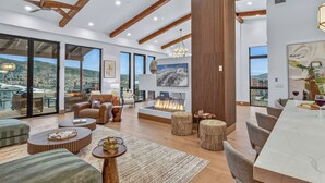 A spacious living room with a fireplace, large windows, and a view of the mountains. - Bold Views, Bright Spaces | Nocturne View (Steamboat Springs)