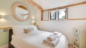 A bedroom with a bed, a round mirror, a dresser, and a window with a view.