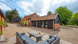 A courtyard with outdoor seating, a building with a tiled roof, and a gravel ground.