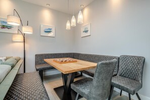 A modern dining area with a wooden table, cushioned benches, and pendant lighting. - 5 Bed in Studland (oc-wy365) (Studland)