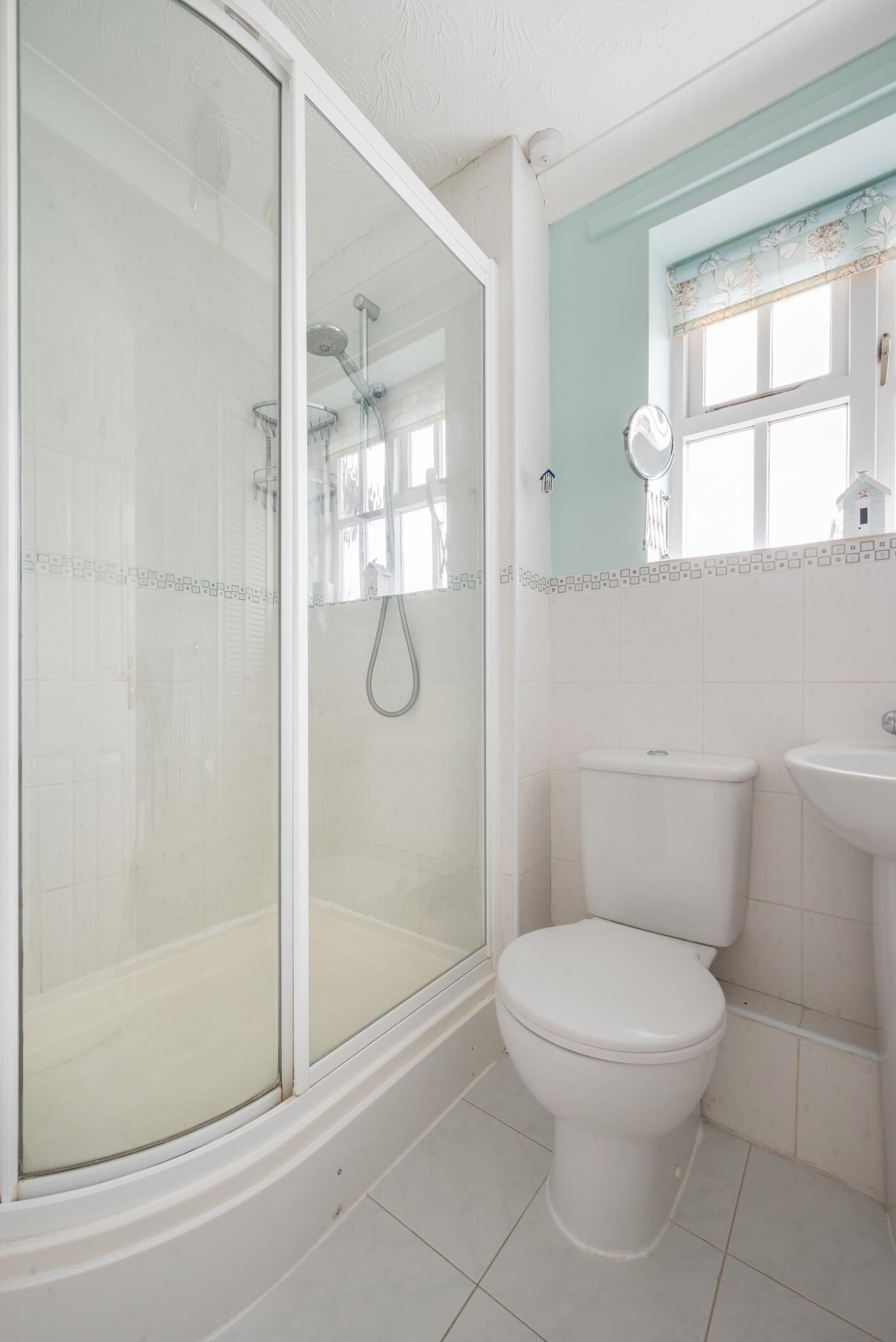 Un baño con ducha envuelta en vidrio, inodoro blanco y lavabo.