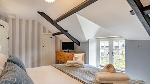 A bedroom with a bed, a wooden dresser, a television, and a window with a view. - 2 Bed in St. Hilary (oc-c33064) (Cowbridge)