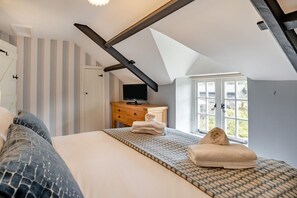 Ein Schlafzimmer mit einem Bett, einer Holzkommode, einem Fernseher und einem Fenster mit Blick.