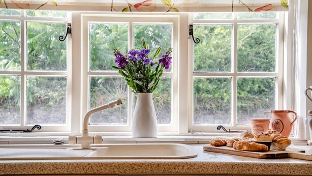 A kitchen with a sink, a vase with flowers, and a window with a view of greenery. - 2 Bed in St. Hilary (oc-c33064) (Cowbridge)
