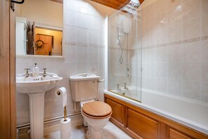Ein Badezimmer mit einem Holzbadezimmermöbel, zwei Waschbecken, einer Toilette und einer Duschkabine.