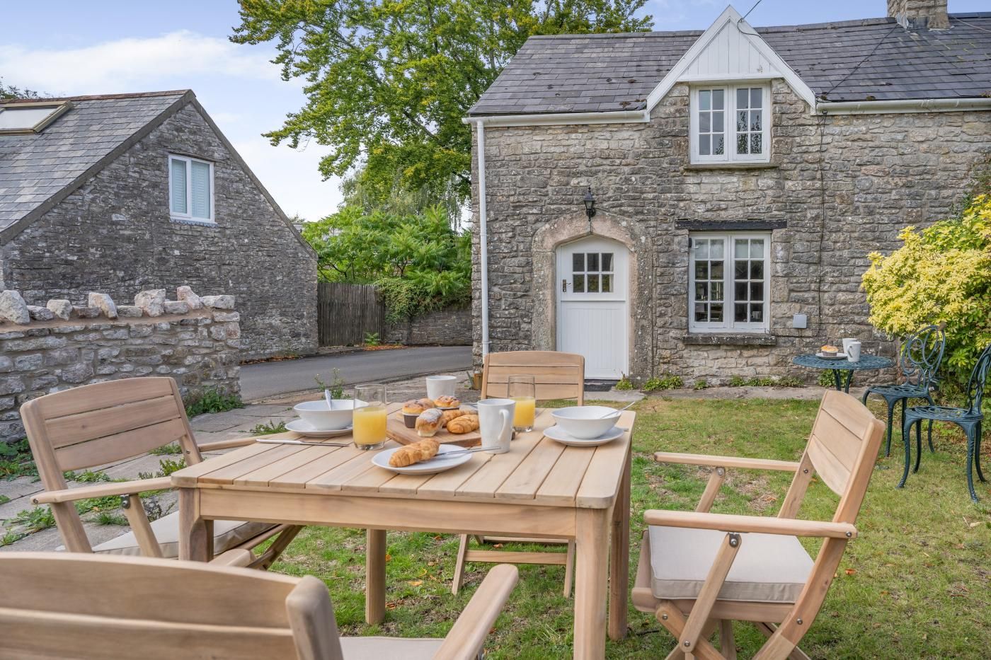 Une maison en pierre avec un espace repas aménagé à l’extérieur.