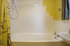 Une salle de bain avec une baignoire, une douche et un lavabo.