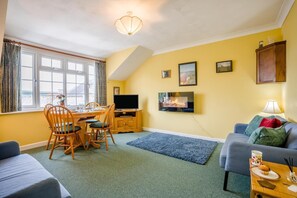 Ein Wohnzimmer mit Essbereich, Fernseher, Kamin und Sofa.