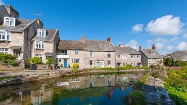 A row of stone buildings with a canal in the foreground. - 1 Bed in Swanage (oc-wy413) (Swanage)