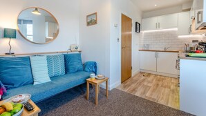 Een modern appartement met woonkamer, kitchenette en een eethoek.