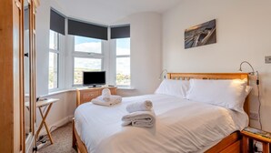Een hotelkamer met een bed, een televisie, een bureau en een raam met uitzicht.