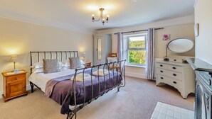 A bedroom with a bed, bedside tables, a dresser, a mirror, and a window with curtains.