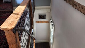 Un escalier avec une rampe en bois, une porte en métal et une petite fenêtre donnant sur une pièce.