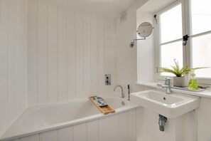 A bathroom with a freestanding bathtub, a sink, and a window with a plant on the windowsill. - 2 Bed in Swanage (oc-wy460) (Swanage)
