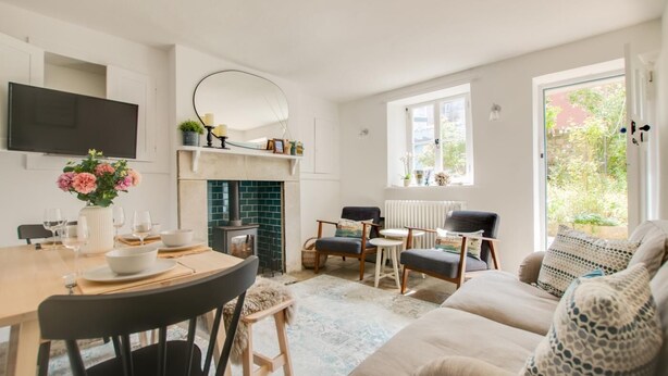 Una sala de estar moderna con chimenea, zona de estar y una mesa de comedor preparada para cuatro.