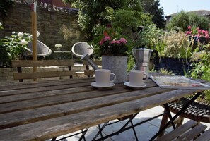 A wooden table with two white cups and saucers, a metal kettle, and a magazine. - 2 Bed in Swanage (oc-wy460) (Swanage)