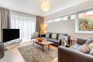 A living room with a flat-screen TV, a sofa, a coffee table, and a rug. - 3 Bed in Southwold (oc-arv) (Southwold)