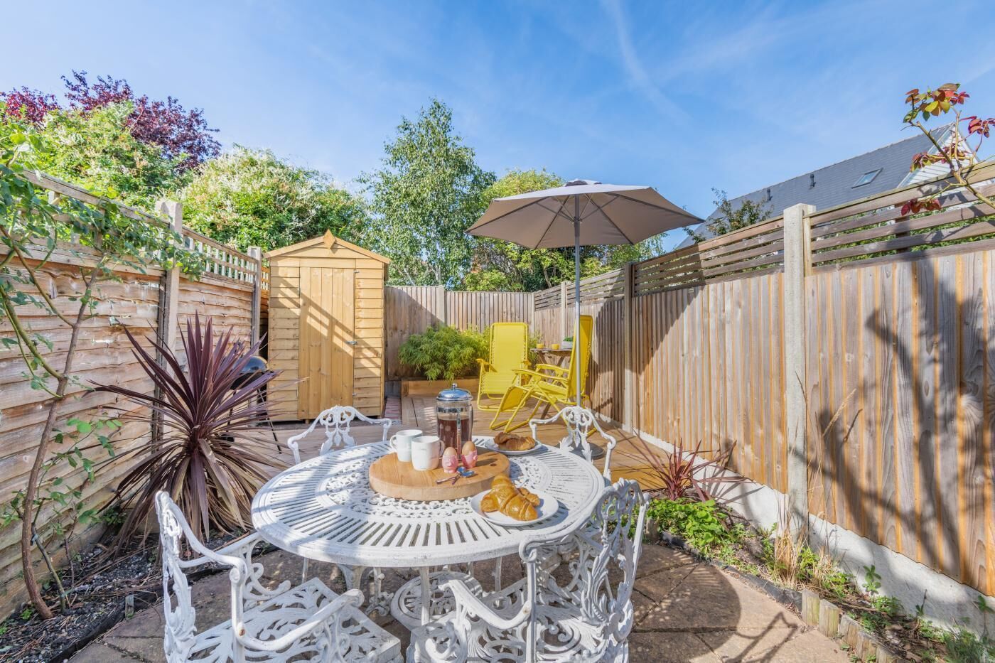 A patio with a round table, chairs, and a wooden shed.