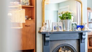 A well-lit room with a wooden cabinet, a mirror, and a mantelpiece with various decorative items. - 2 Bed in Whitstable (oc-o32772) (Whitstable)