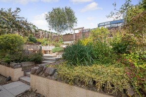 A garden with stone steps, a wooden fence, and a variety of plants.