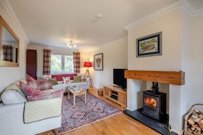 A cozy living room with a sofa, a coffee table, a fireplace, and a television.