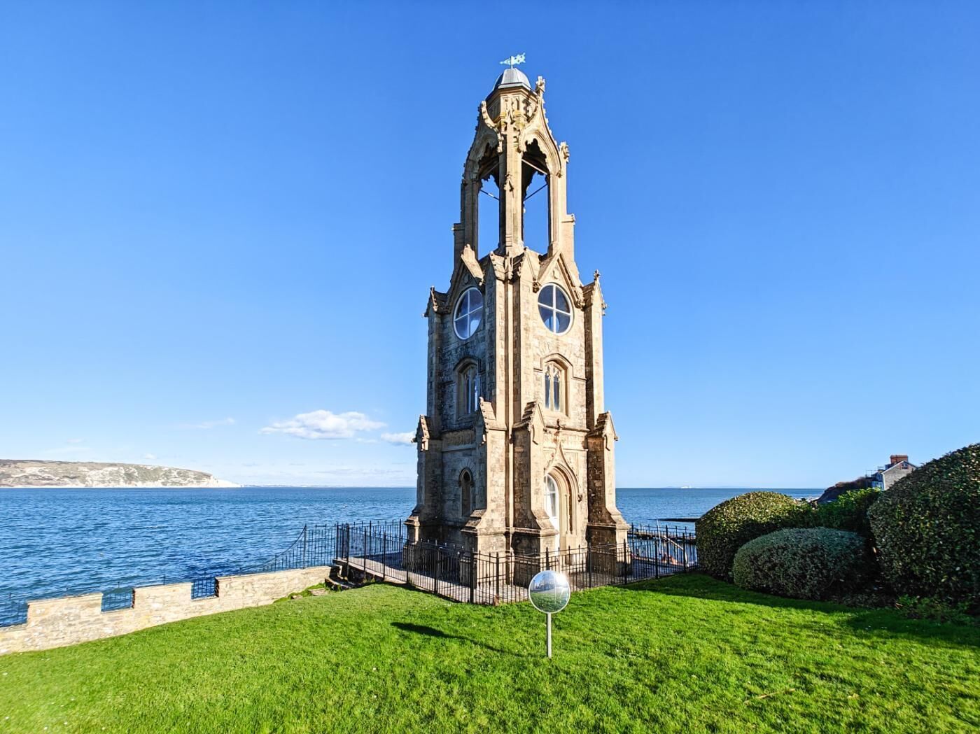 Una torre histórica con un reloj, cerca de un cuerpo de agua.