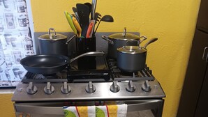 Ett kök med en spis, kastruller och en mikrovågsugn.