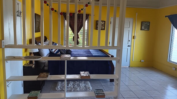 Una habitación con una cama litera, ventilador de techo y ventana con cortinas.