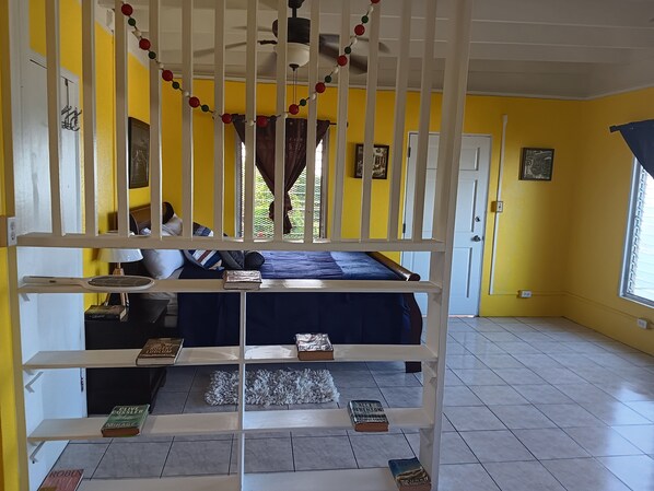 A room with a bunk bed, a ceiling fan, and a window with curtains.