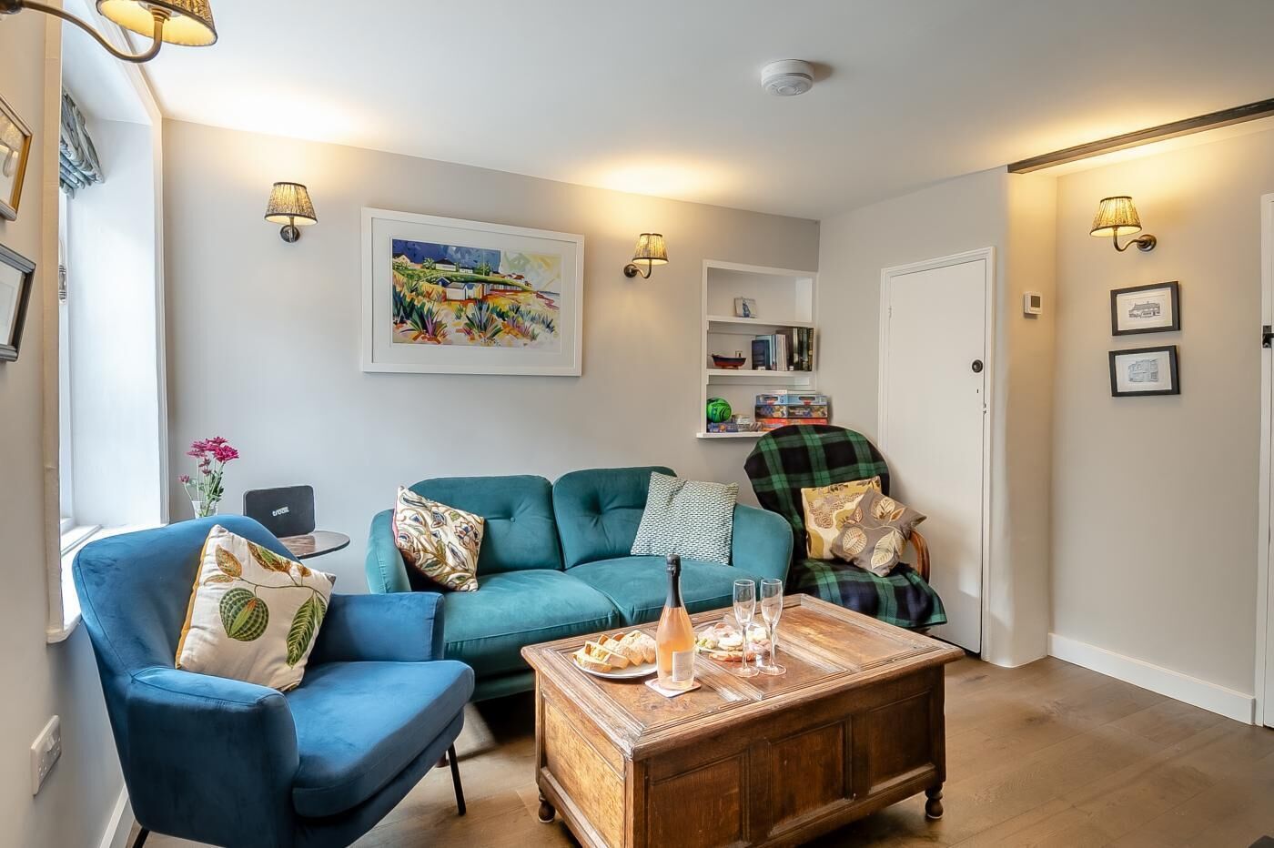 A living room with a blue sofa, a wooden coffee table with snacks and glasses, and a painting on the wall.