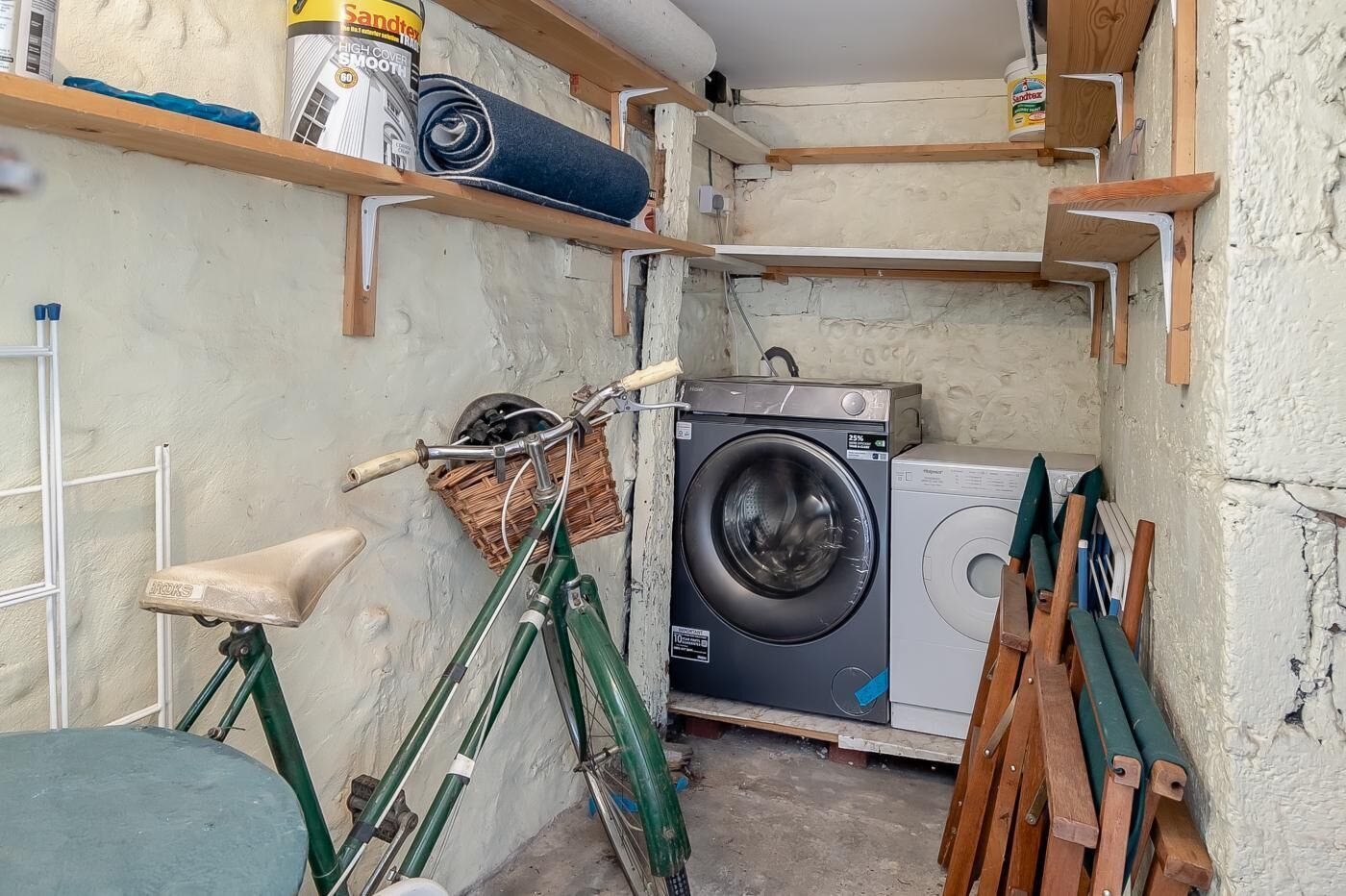 A laundry room with a washing machine, a bicycle, and shelves with cleaning supplies.