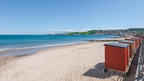 Ein Strand mit einer Reihe roter Strandhütten am Ufer.