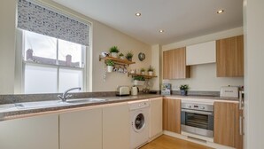 Eine moderne Küche mit eingebauter Waschmaschine, Brotbackmaschine und Holzschränken.